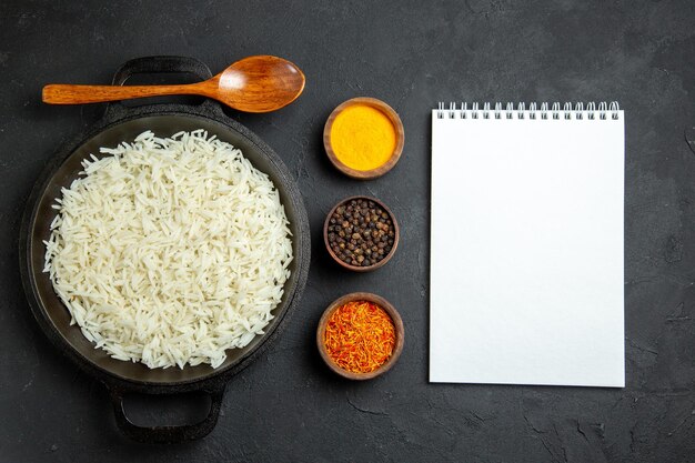 Vista dall'alto riso cotto all'interno della padella con condimenti sulla superficie scura pasto cibo cena orientale eastern