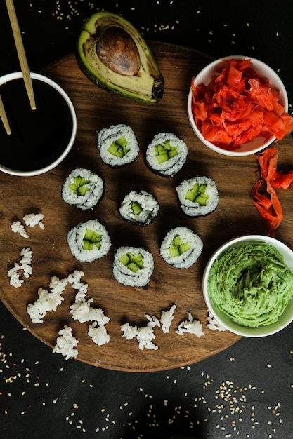 Vista dall'alto rotoli di kappa maki su un supporto con salsa di soia allo zenzero avacado bollito riso e wasabi