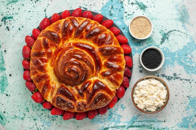 Vista dall'alto rotonda deliziosa torta con fragole rosse fresche su superficie azzurra