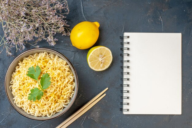 Vista dall'alto spaghetti ramen asiatici in una ciotola limone e tagliare il taccuino di bacchette di limone sul tavolo scuro