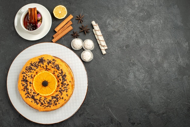 Vista dall'alto squisita torta dolce con arancia e tazza di tè sulla superficie grigia torta dolce torta biscotto tè