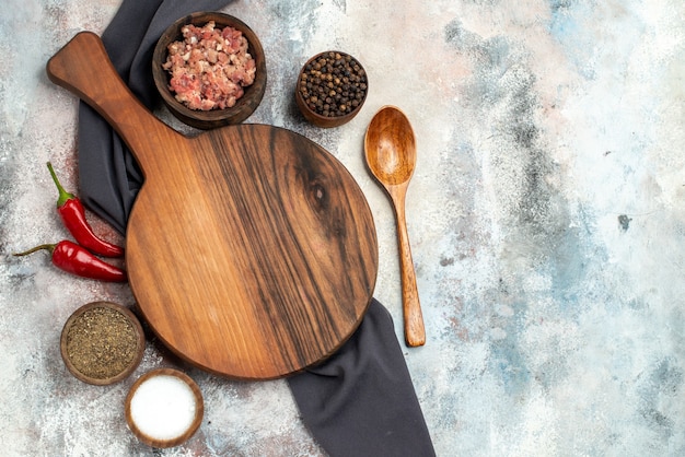 Vista dall'alto tagliere tovaglia nera ciotole con carne diverse spezie cucchiaio di legno sulla superficie nuda copia spazio