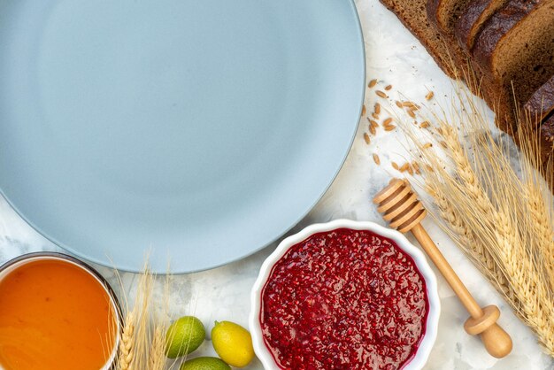 Vista dall'alto tavolo per la colazione con piatto blu uova marmellata gelatina pane scuro su sfondo bianco torta di pasta al caffè tè del mattino panino all'uovo