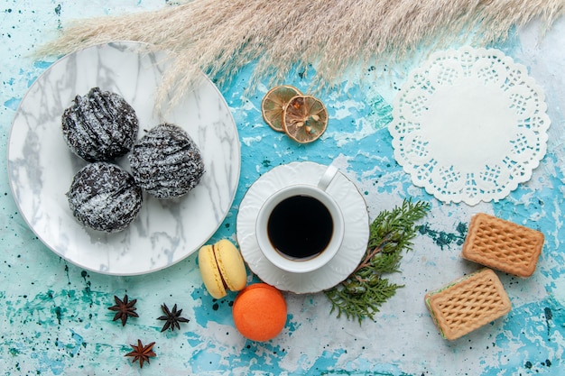 Vista dall'alto tazza di caffè con macarons francesi cialde e torte al cioccolato sulla scrivania blu torta cuocere biscotti al cioccolato dolce zucchero colore