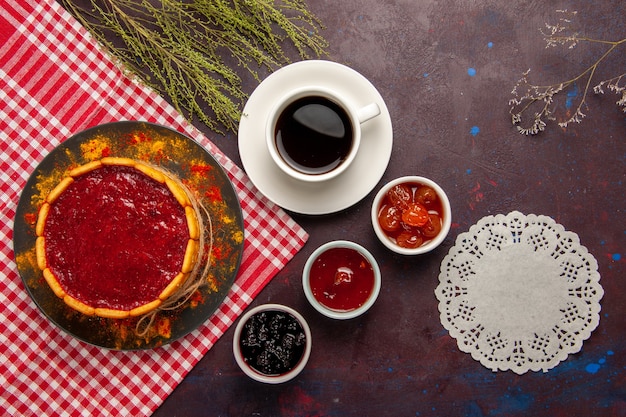 Vista dall'alto tazza di caffè con una deliziosa torta da dessert e marmellate di frutta su sfondo scuro dolce frutta biscotto biscotto dolce