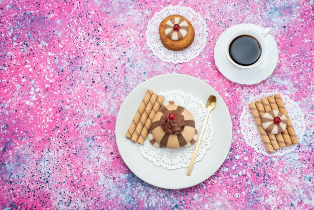 Vista dall'alto tazza di caffè insieme a biscotti al cioccolato sullo sfondo colorato biscotto color caffè biscotto