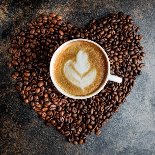 Vista dall'alto tazza di cappuccino e chicchi di caffè sotto forma di un cuore