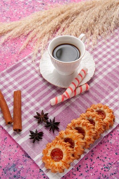 Vista dall'alto tazza di tè con biscotti e cannella sulla scrivania rosa biscotto zucchero biscotto dolce