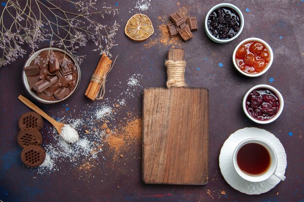 Vista dall'alto tazza di tè con biscotti e marmellata su uno spazio buio