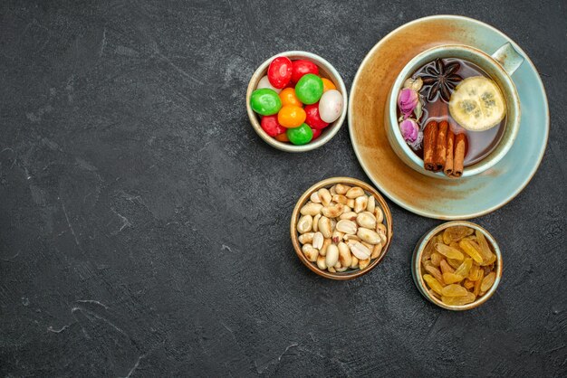 Vista dall'alto tazza di tè con caramelle e noci su spazio grigio