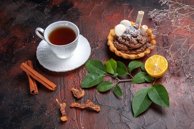 Vista dall'alto tazza di tè con deliziosa piccola torta sul biscotto da dessert biscotti tavolo scuro