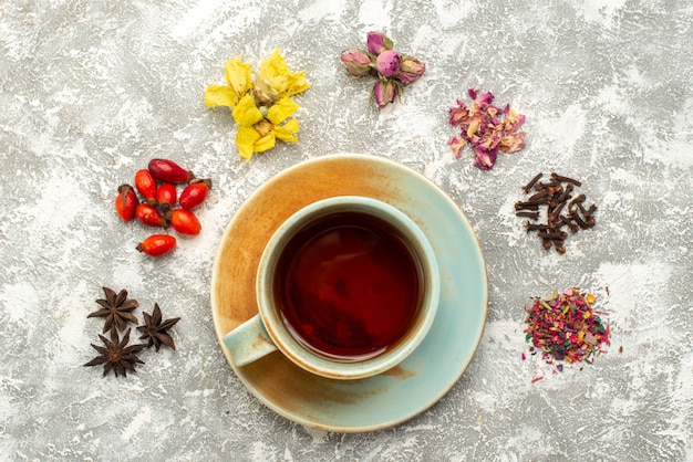 Vista dall'alto tazza di tè con fiori secchi su superficie bianca bevanda al tè sapore di fiori