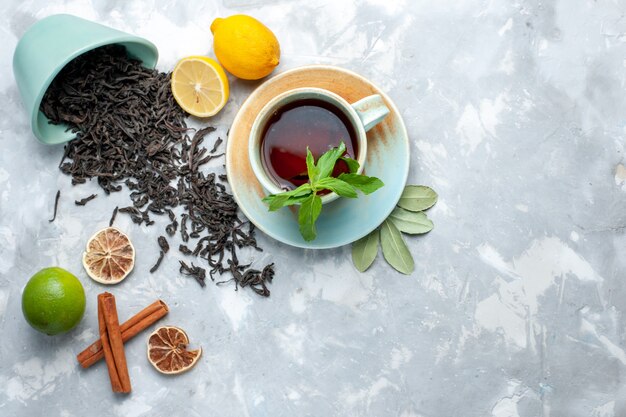 Vista dall'alto tazza di tè con limone e cannella sul tavolo luminoso, agrumi di colore secco di tè di grano