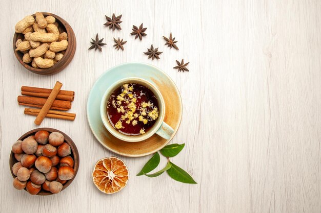 Vista dall'alto tazza di tè con noci diverse sulle noci di cerimonia della frutta del tè di colore bianco della scrivania