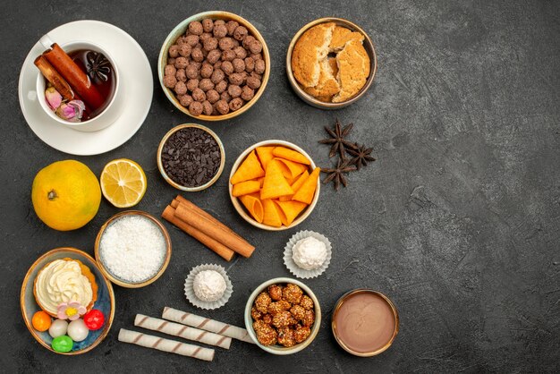 Vista dall'alto tazza di tè con patatine e torta sulla superficie scura biscotto caramelle biscotto torta torta dolce