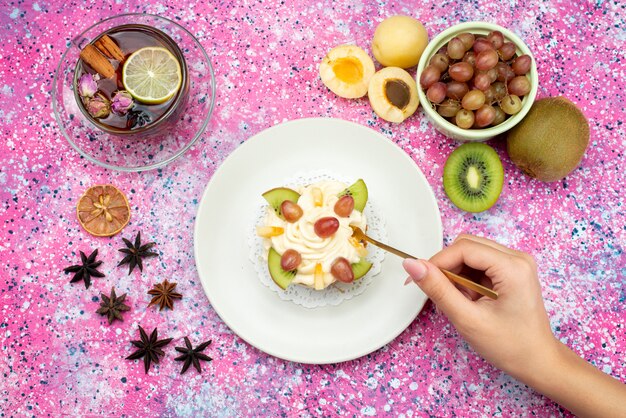 Vista dall'alto torta alla crema con kiwi albicocche e tè sullo sfondo colorato torta zucchero pasta dolce cuocere i frutti