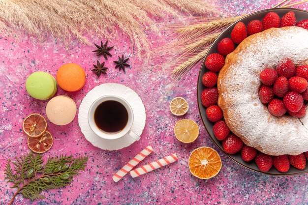 Vista dall'alto torta di fragole torta di zucchero in polvere con una tazza di tè sul rosa