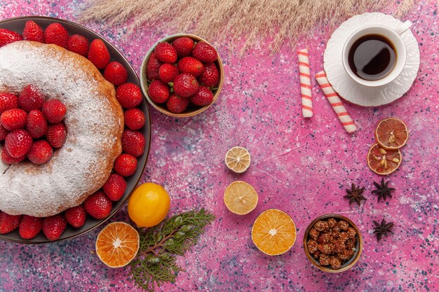 Vista dall'alto torta di fragole torta di zucchero in polvere con una tazza di tè sul rosa