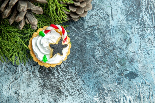 Vista dall'alto torta di Natale rami di pino pigne nelle quali sul tavolo grigio con spazio libero