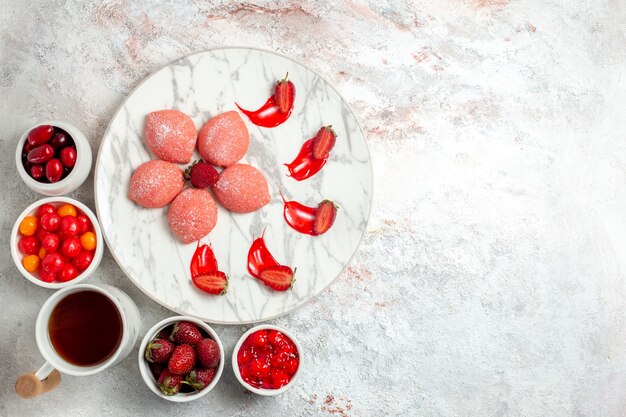 Vista dall'alto torte di fragole rosa con frutta su sfondo bianco torta zucchero biscotto biscotto da tè dolce