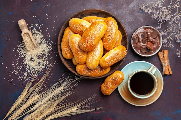 Vista dall'alto tortini dolci con una tazza di tè e cioccolato sullo sfondo scuro tortino di cibo di tè pasta pasticceria pasto