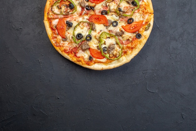 Vista dall'alto una deliziosa pizza al formaggio con olive, pepe e pomodori sulla superficie scura