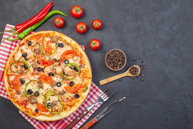 Vista dall'alto una deliziosa pizza al formaggio con olive, pepe e pomodori sulla superficie scura