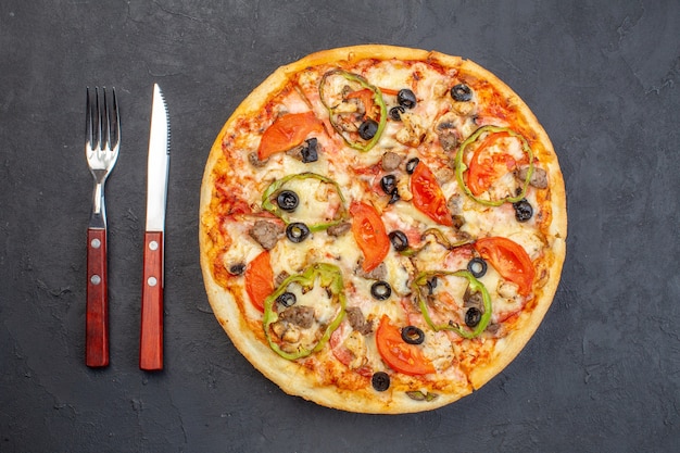 Vista dall'alto una deliziosa pizza al formaggio con olive, pepe e pomodori sulla superficie scura