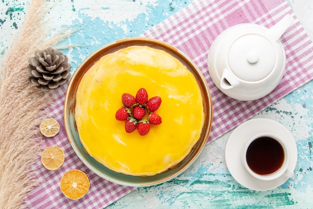 Vista dall'alto una deliziosa torta con sciroppo giallo e fragole rosse fresche sulla superficie azzurra torta biscotto cuocere tè dolce torta di zucchero