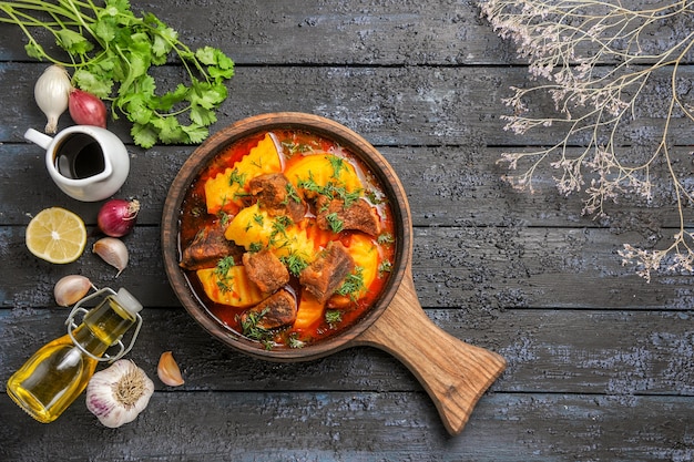 Vista dall'alto una deliziosa zuppa di carne con patate e verdure sulla scrivania scura