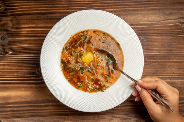 Vista dall'alto una deliziosa zuppa di verdure con verdure su condimenti vegetali di cibo zuppa di tavolo marrone