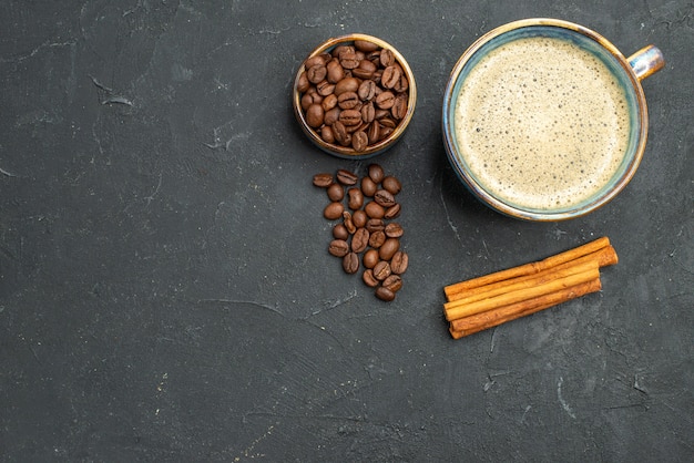 Vista dall'alto una tazza di caffè ciotola con semi di caffè bastoncini di cannella su sfondo scuro isolato