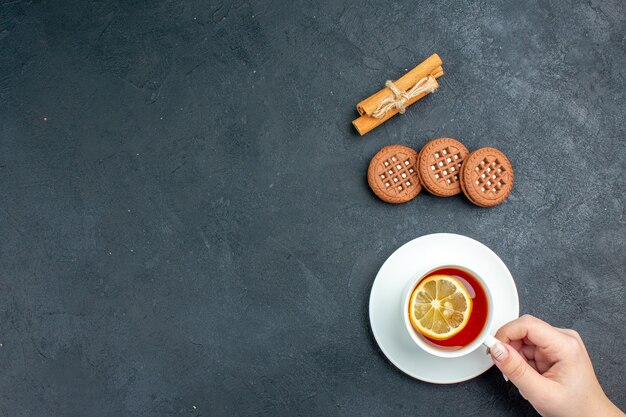 Vista dall'alto una tazza di tè con biscotti al limone e bastoncini di cannella sulla superficie scura con spazio di copia