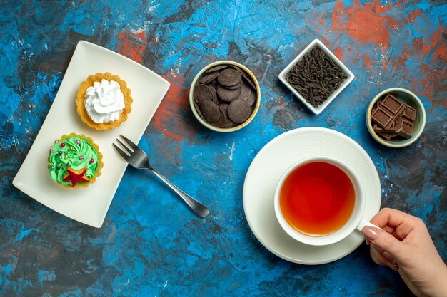 Vista dall'alto una tazza di tè piccoli dolci al cioccolato sulla superficie rossa blu