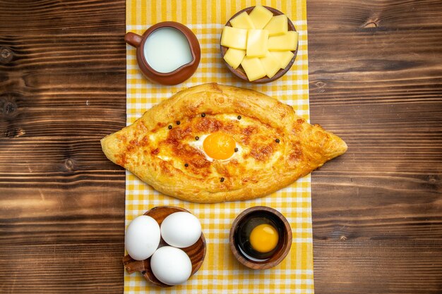 Vista dall'alto uova crude con formaggio a fette e latte sulla superficie in legno prodotto uova pasta pasto cibo crudo