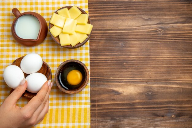 Vista dall'alto uova crude con formaggio e latte su fondo in legno prodotto uova pasta pasto cibo crudo