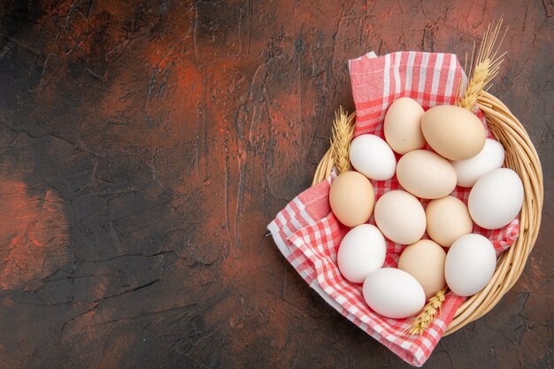 Vista dall'alto uova di gallina bianca all'interno del cesto con asciugamano sul tavolo scuro