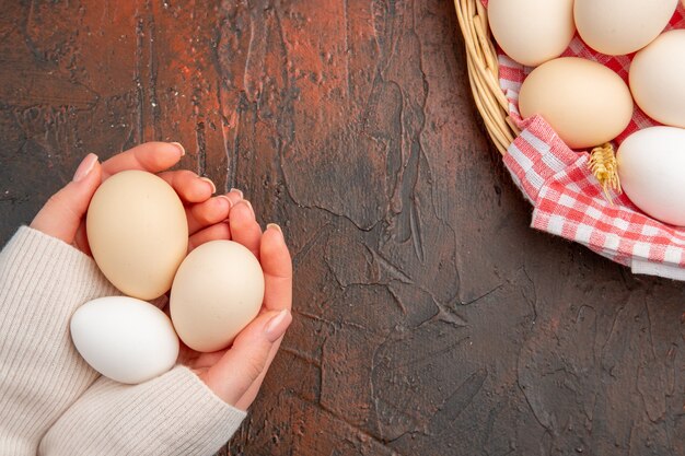 Vista dall'alto uova di gallina bianche all'interno del cesto con asciugamano sul tavolo scuro cibo fattoria degli animali colazione pasto foto a colori crudo