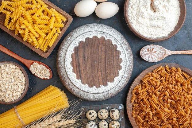 Vista dall'alto uova fresche con pasta cruda di cereali e farina su sfondo scuro pasta cuocere il pasto fotografico a colori