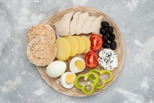 Vista dall'alto Uova sode con condimenti di seni di olive e pomodori su grigio, pasto vegetale colazione