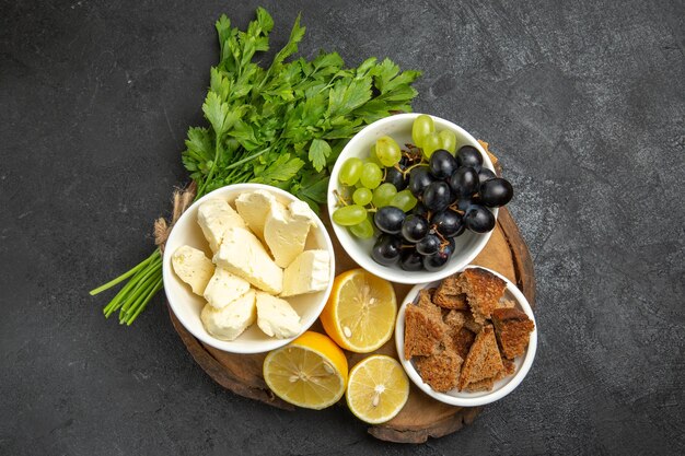 Vista dall'alto uva fresca con verdure al formaggio bianco e fette di limone sulla superficie scura pasto frutta latte cibo