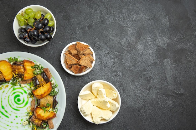 Vista dall'alto uva fresca e dolce con formaggio bianco e involtini di melanzane su frutti di latte pasto di superficie scura