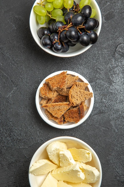 Vista dall'alto uva fresca e morbida con pane e formaggio su frutta latte pasto superficie scura