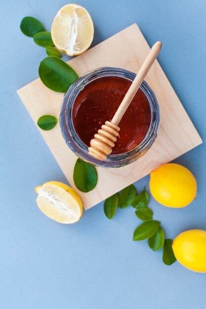 Vista dall'alto vaso di miele sul tavolo con limoni