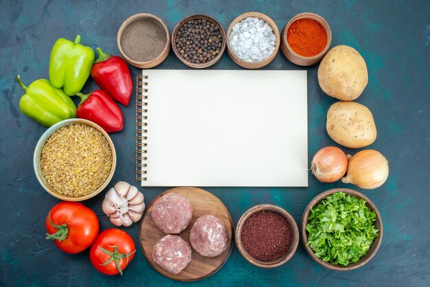 Vista dall'alto verdure fresche con condimenti carne e verdure sulla superficie blu scuro