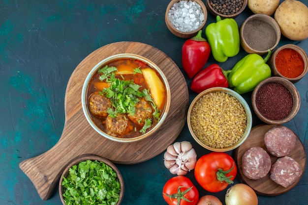 Vista dall'alto verdure fresche con condimenti zuppa di carne e verdure sulla scrivania blu scuro