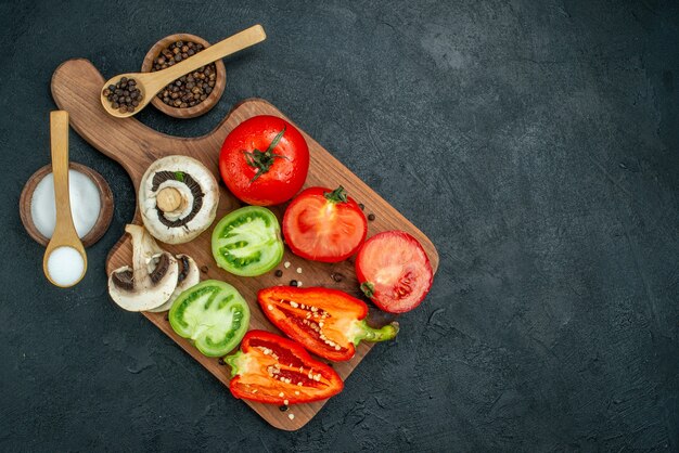 Vista dall'alto verdure fresche funghi pomodori rossi e verdi peperoni sul tagliere