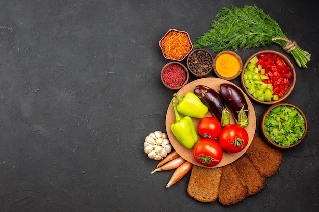 Vista dall'alto verdure fresche mature con verdure e pagnotte di pane scuro sulla superficie scura insalata cibo pasto salute vegetale