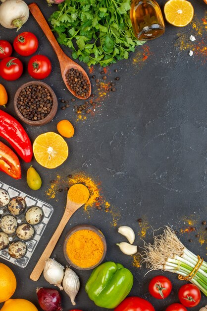 Vista dall'alto verdure fresche pepe nero e curcuma in piccole ciotole cucchiai di legno bottiglia di olio uova di quaglia sul tavolo spazio libero