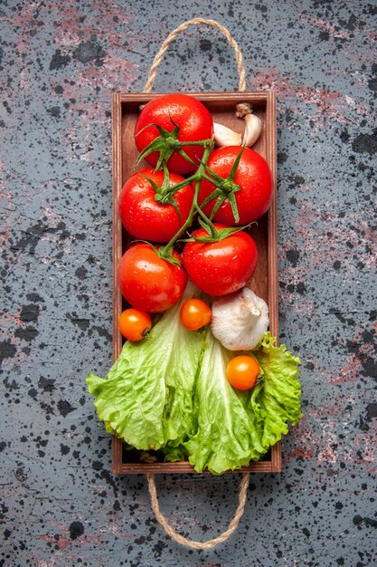 vista dall'alto verdure fresche pomodori rossi aglio e insalata verde all'interno della tavola di legno sulla superficie blu colore del cibo insalata di pranzo pasto maturo